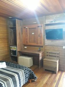 a bedroom with a television and a bed and a desk at Pousada e Restaurante Redivo in Louro Müller