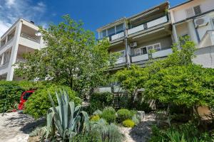 an apartment building with a garden in front of it at Apartments & Rooms Rica in Makarska