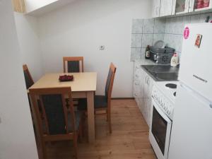 Una pequeña cocina con una mesa y sillas y una estufa. en Apartman M, en Soko Banja 5 fotos más