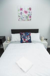 uma cama branca com duas mesas e uma pintura na parede em Blueville House, Bluewater, 4 Bedroom Houses, Greenhithe, Dartford, Kent-Hosted by Castile Accommodations Ltd em Kent