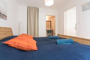 łóżko z 2 pomarańczowymi i niebieskimi poduszkami w obiekcie Bright Apartment in Hip & High Quality Neighborhood w Wiedniu