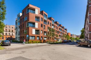 un gran edificio de ladrillo en una calle de la ciudad con coches aparcados en Happy Stay OldNova Deluxe Apartment 366, en Gdansk