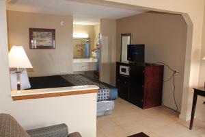 a small hotel room with a bed and a television at Highland Inn Denham Springs Baton Rouge East in Denham Springs