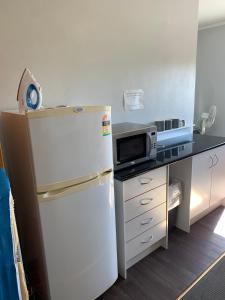 eine Küche mit einem Kühlschrank und einer Mikrowelle in der Unterkunft Kootingal Hotel in Kootingal