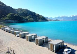a row of mobile homes on a beach next to the water at Chelenko Lodge in Puerto Tranquilo