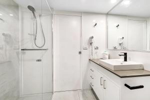 a white bathroom with a shower and a sink at Surfers Century Oceanside Apartments in Gold Coast