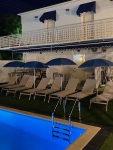eine Gruppe von Stühlen und Sonnenschirmen neben einem Pool in der Unterkunft Saint George Hotel in Asprovalta