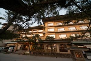 un grand bâtiment jaune avec des arbres devant lui dans l'établissement Hotel Miya Rikyu, à Miyajima