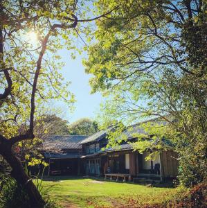 a house in the middle of a yard with trees at Kominka Sharehouse Hooju in Miyazaki