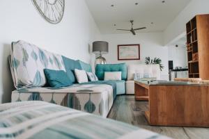 a living room with a blue couch and a table at Sunset Palm - Villa Créole avec piscine face au coucher de soleil et à la réserve Cousteau in Bouillante