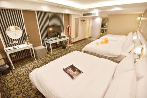 a hotel room with two beds and a television at Migo Hotel in Taichung