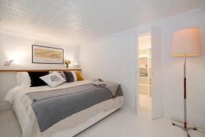 a white bedroom with a bed and a lamp at Beachside Loft St Kilda west in Melbourne