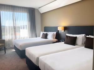 a hotel room with two beds and a window at Sudima Auckland Airport in Auckland