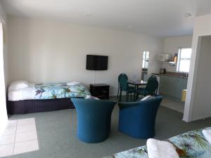 1 dormitorio con 1 cama, mesa y sillas en Blake Court Motel, en Whangamata