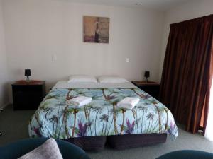 a bedroom with a bed with two towels on it at Blake Court Motel in Whangamata