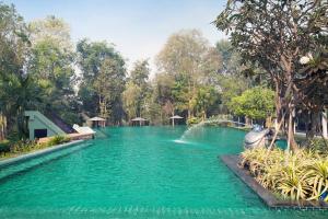 een zwembad van blauw water met bomen op de achtergrond bij Mida Resort Kanchanaburi - SHA PLUS in Sai Yok