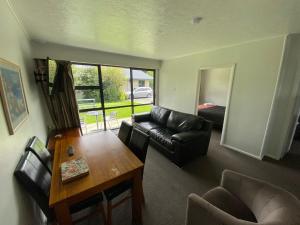 uma sala de estar com uma mesa e um sofá em Grove Park Motor Lodge em Blenheim