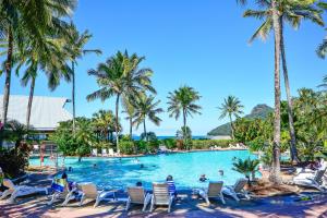 a pool at a resort with people in chairs and palm trees at Heliconia Grove 9 in Hamilton Island