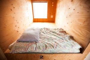 Bett in einem Holzzimmer mit Fenster in der Unterkunft Sunset Breeze Hota in Kyonan