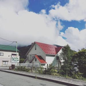 a white house with a red roof on a street at Little Forest Inn Nikko in Nikko