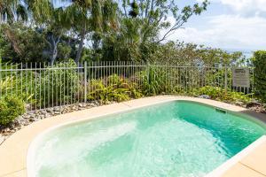 a small swimming pool in front of a fence at Ocean Sunsets - Skiathos in Hamilton Island
