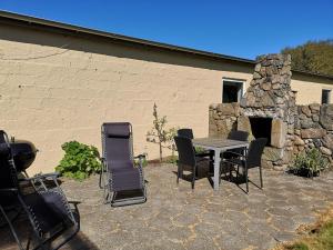 a patio with a table and chairs and a stone fireplace at Logi i hus med kunst og have in Vestervig