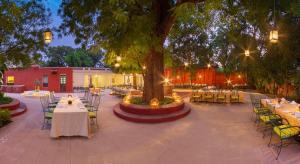 dziedziniec ze stołami, krzesłami i drzewem w obiekcie Sawai Madhopur Lodge - IHCL SeleQtions w mieście Sawai Madhopur