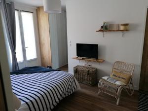 a bedroom with a bed and a tv and a chair at Chambre Studio Les Deux Vagues in Sangatte