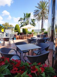een patio met tafels en stoelen en palmbomen bij Hotel Carmen in La Carlota