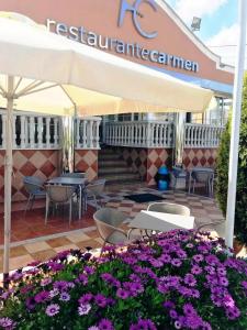 a restaurant with tables and chairs and purple flowers at Hotel Carmen in La Carlota