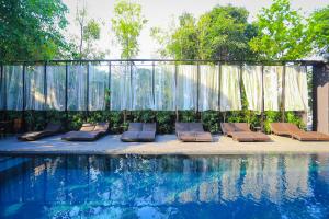 a group of lounge chairs next to a swimming pool at BED Nimman - Adults Only in Chiang Mai