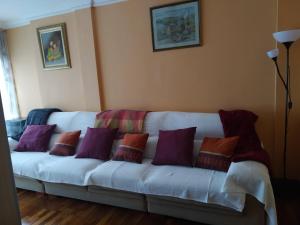 eine weiße Couch mit lila und orangefarbenen Kissen darauf in der Unterkunft Apartamento Trapagaran in Trapagaran