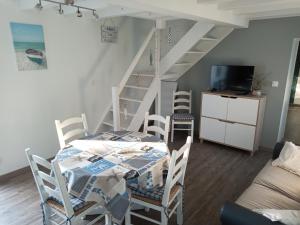 ein Esszimmer mit einem Tisch, Stühlen und einer Treppe in der Unterkunft maison "Le Goéland" à deux pas des plages in Longeville-sur-Mer