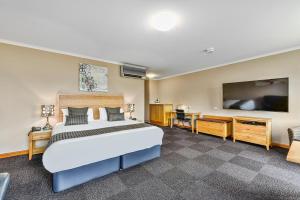 a bedroom with a large bed and a flat screen tv at Southgate Motel in Mount Gambier