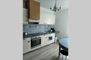 a kitchen with white cabinets and a table and a chandelier at Le gîte de Georgette in Cour-Cheverny