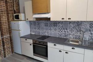 a kitchen with white cabinets and a sink and a refrigerator at Le gîte de Georgette in Cour-Cheverny