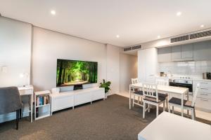 a kitchen and dining room with a tv on the wall at Horizons 1402 in Adelaide