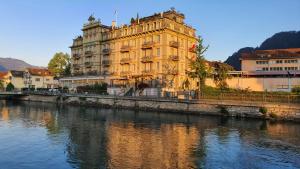 a large building next to a river with buildings at Hotel Central Continental in Interlaken