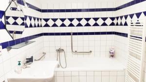 een badkamer met blauwe en witte betegelde muren en een wastafel bij Bakarloko Lipno Apartments in Lipno nad Vltavou