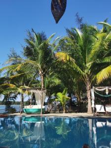 una piscina con palme sullo sfondo di Le Domaine De Tam Hai Resort ad An Hòa