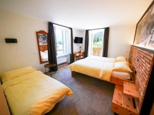 een slaapkamer met 2 bedden en 2 ramen bij Hôtel du Glacier in Champex