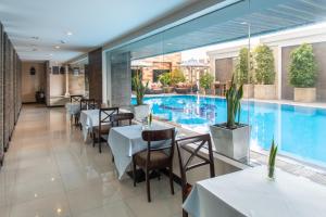 a restaurant with a swimming pool and tables and chairs at Mida Hotel Don Mueang Airport in Bangkok