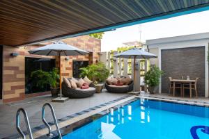 a swimming pool with chairs and umbrellas next to a house at Mida Hotel Don Mueang Airport in Bangkok