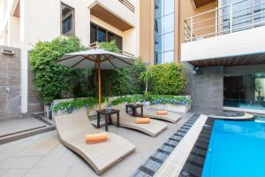 a patio with chairs and an umbrella next to a pool at Mida Hotel Don Mueang Airport in Bangkok