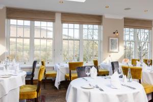 Losehill House Hotel & Spa في هوب: مطعم بطاولات بيضاء وكراسي ونوافذ صفراء