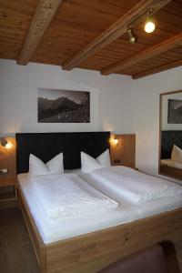 een slaapkamer met een groot bed met witte lakens bij Landhaus Edelweiß in Mittelberg