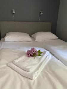 a white towel with a bouquet of flowers on a bed at Kragerø Sportell & Apartments in Kragerø