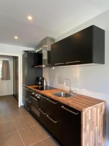 a kitchen with black cabinets and a sink at Kragerø Sportell & Apartments in Kragerø