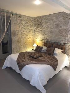 a bedroom with a large bed with a stone wall at Domaine de La Michelle in Madaillan