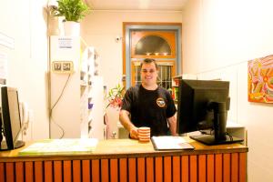 a man standing behind a desk with a computer at Original Backpackers in Sydney